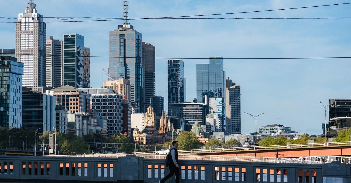 Commuter walking past the Melbourne city skyline, the setting for a migration agent Melbourne review of 2027 skilled pathways