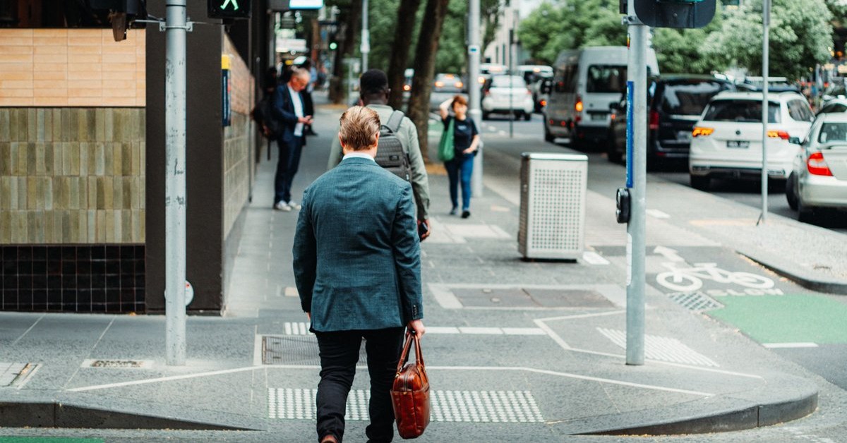 Professional crossing an Australian city street on a green signal, representing a clear path through Australia PR requirements