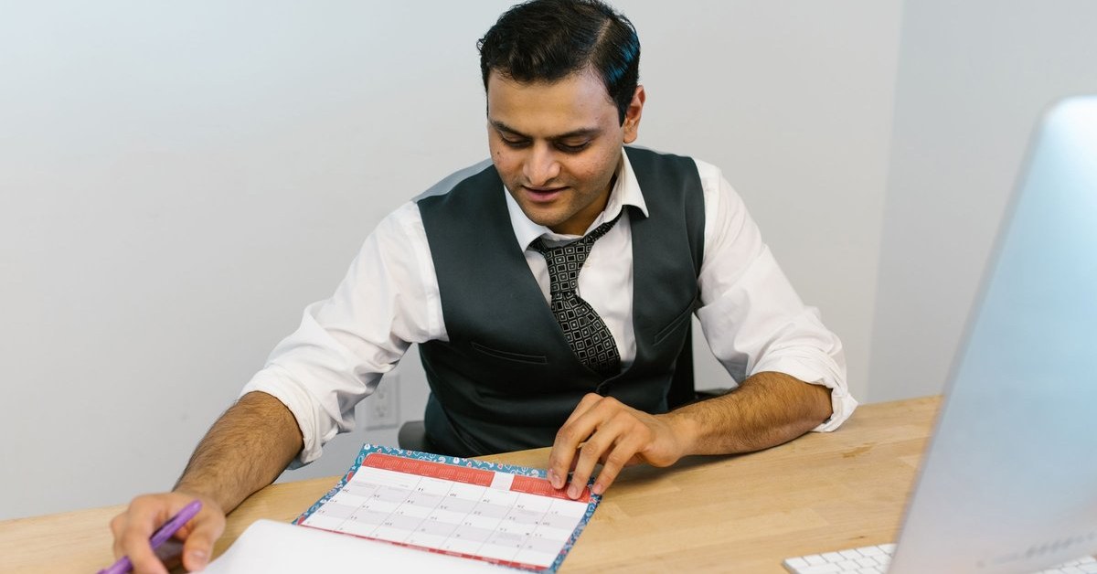 Man checking a desk calendar at his desk while planning around the Australia PR age limit